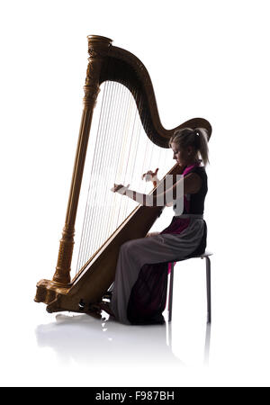 Silhouette of elegant woman in dress playing the harp, isolated on white background Stock Photo