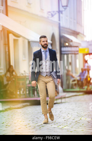 Handsome hipster modern businessman with briefcase walking in town Stock Photo