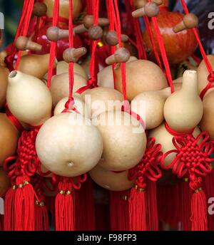 An outdoor vendor sells dried bottle gourds that are decorated with red ribbons Stock Photo