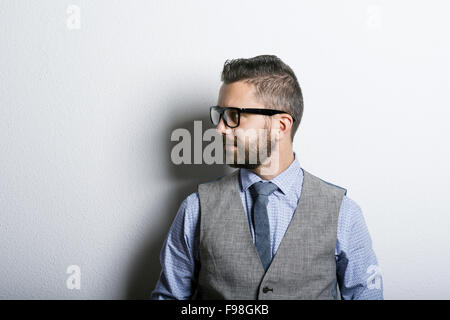 Studio shot of modern hipster businessman leaning against wall Stock Photo