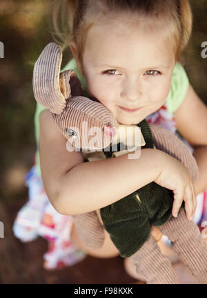 Outdoor portrait of cute little girl holding her toy Stock Photo