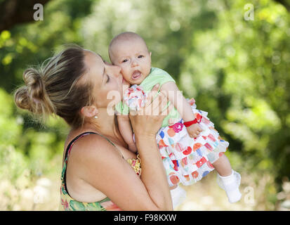 Happy young mother spending time with her baby daughter in green nature. Stock Photo