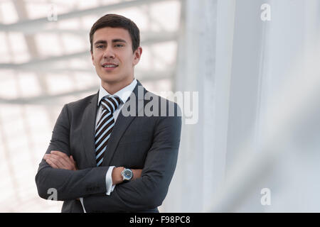 Portrait of handsome confident young businessman standing arms crossed, smiling happy, looking at camera. Stock Photo