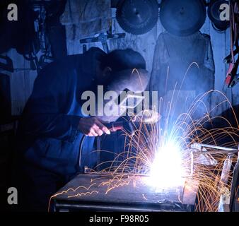 Man welding wearing protective clothing in a workshop, Aldridge, West Midlands, UK, Western Europe. Stock Photo
