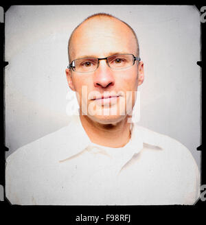 Portrait of a middle aged athletic man. He is wearing a white shirt, wears glasses, and appears very relaxed and comfortable in front of a camera. Grain, scratches, and a border were given to the photograph to soften it up. Stock Photo