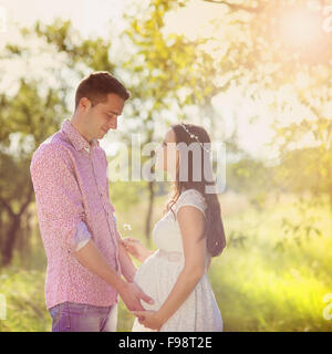 Happy and young pregnant couple hugging in nature Stock Photo