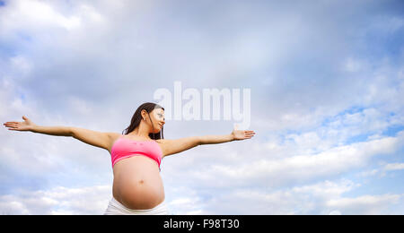 Happy young pregnant woman exercising in summer nature Stock Photo