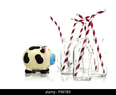 Milk bottles with red and white striped straws and inquisitive cow on white background Stock Photo