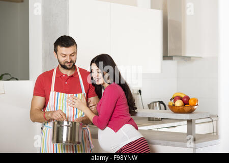 Pregnant woman and happy man in the kitchen Stock Photo