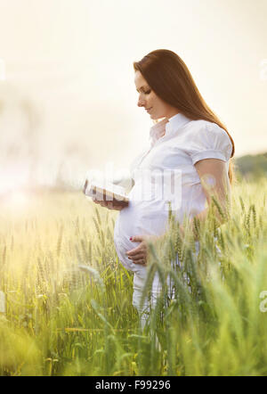 Outdoor portrait of young pregnant woman praying in the field Stock Photo