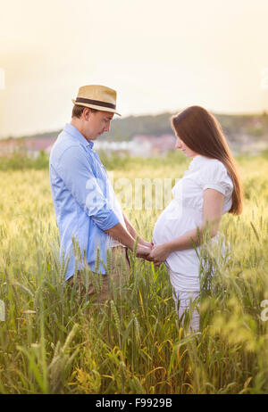 Outdoor portrait of young pregnant couple in field Stock Photo