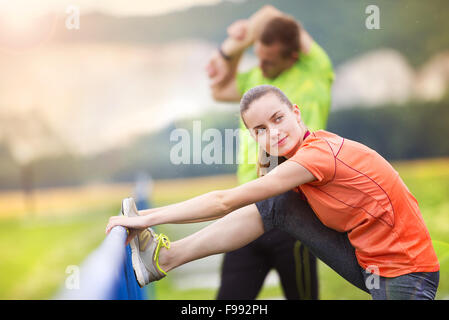 Young couple stretching after the run on asphalt in rainy weather Stock Photo