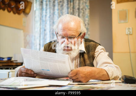 Old man reading the newspaper at home Stock Photo