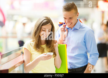 Happy young couple with bags in shopping mall Stock Photo