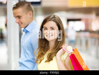 Happy young couple with bags in shopping mall Stock Photo