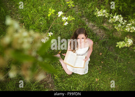 Beutiful young woman reading book in green park Stock Photo