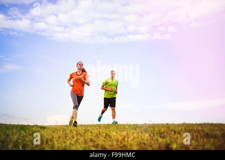 Cross-country trail running people at sunset. Runner couple exercising outside as part of healthy lifestyle. Stock Photo