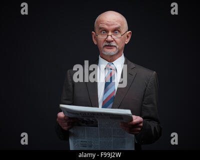 Mature businessman reading newspaper with breaking news Stock Photo