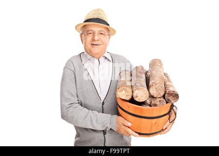 Cheerful senior gentleman carrying a pile of logs in a wooden basket isolated on white background Stock Photo