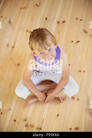 Blonde girl sitting on the wooden floor in house Stock Photo
