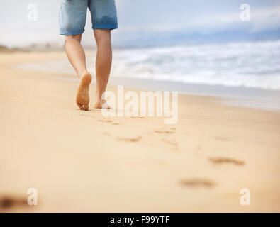 Detail of male feet walking at the sandy beach Stock Photo