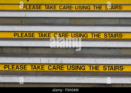 Please take care using the Stairs yellow information signs on steps Stock Photo