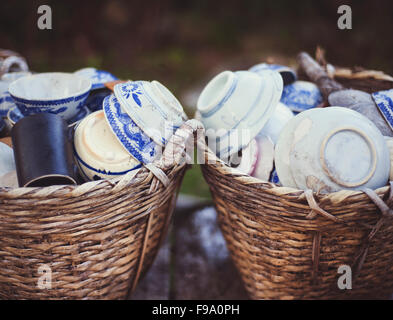 Cheap ceramic cups, plates and bowls in basket on a street market for sale in Vietnam Stock Photo