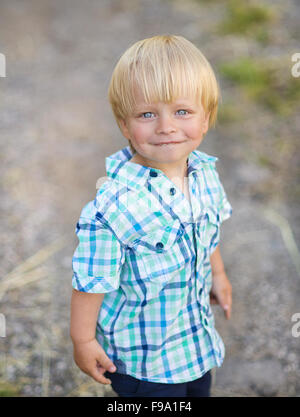 Portrait of blonde little boy posing outside. Cute child enjoy warm ...