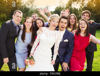 Portrait of newlywed couple having fun with bridesmaids and groomsmen in green sunny park Stock Photo