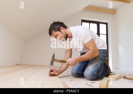 Handyman installing wooden floor in new house Stock Photo