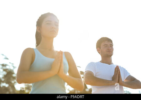 Fitness, sport, friendship and lifestyle concept - smiling couple making meditation yoga exercises on beach at morning Stock Photo