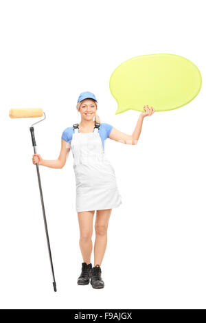 Full length portrait of a female painter holding a paint roller and a big yellow speech bubble isolated on white background Stock Photo