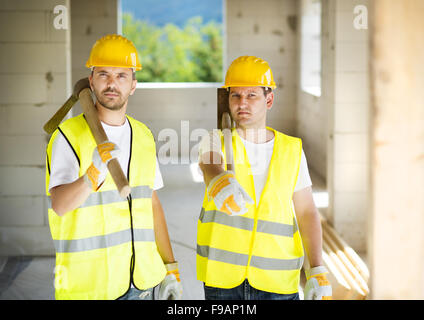 Construction workers collaborating on new house building Stock Photo