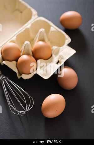 Brown eggs and whisk on the black slate Stock Photo
