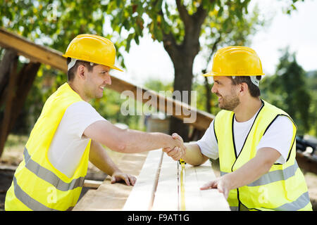 Construction workers collaborating on new house building Stock Photo