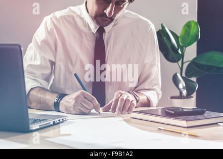 Businessman sketching business diagram, working overtime at office desk, multitasking and project deadline concept, retro toned Stock Photo