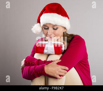 Beautiful christmas woman is holding red gift in studio Stock Photo