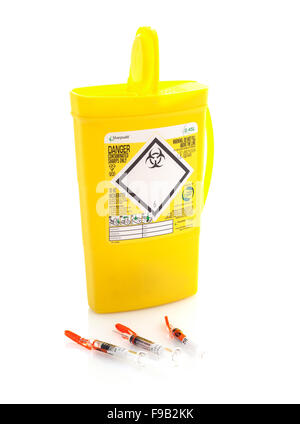 Yellow medical sharps disposal box with three hypodermics on a White Background Stock Photo