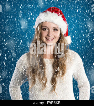 Beautiful woman wearing christmas hat on blue winter background with snowflakes Stock Photo