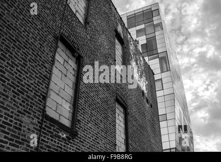 A contrast of an old brick building with a modern glass tower in monochrome. Shot in NYC. Stock Photo