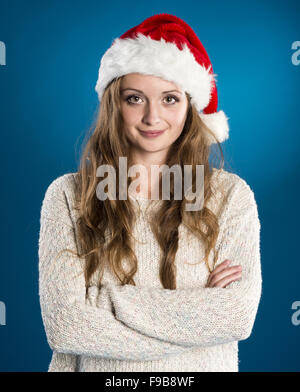 Beautiful woman wearing christmas hat on blue winter background with snowflakes Stock Photo
