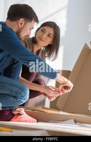 Happy young couple putting together self assembly furniture as they move into their new house. Stock Photo