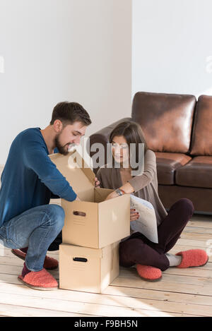 Happy young couple putting together self assembly furniture as they move into their new house. Stock Photo