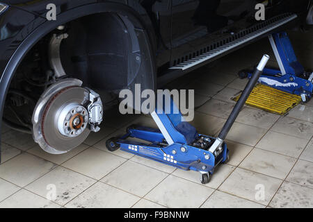 Car repairs service. The car with the dismantled wheels on two hydraulic jacks. Stock Photo