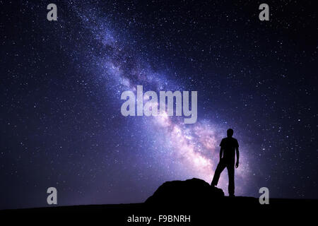 Milky Way. Night sky with stars and silhouette of a man with raised-up arms Stock Photo