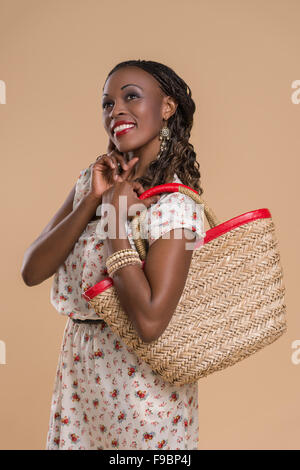 Portrait of cute african woman posing - standing with straw bag Stock Photo