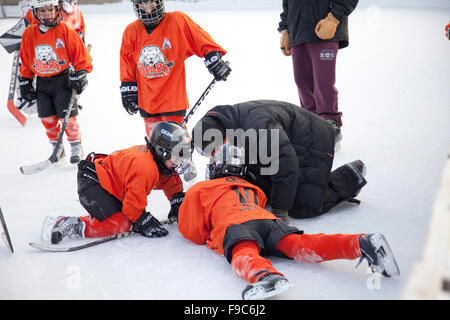 Coach talking to injured boy age 10 downed during an outdoor hockey game. Phalen Park Recreation Center St Paul Minnesota MN USA Stock Photo