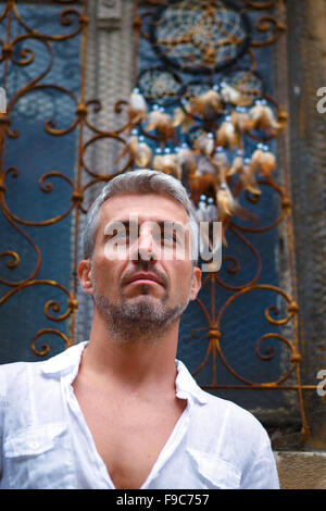 Sexi Man in a white shirt and ornamental window on background. And Dream Catcher Stock Photo