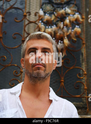 Sexi Man in a white shirt and ornamental window on background. And Dream Catcher Stock Photo