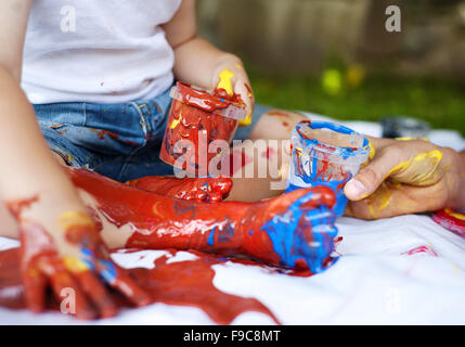 Cute child painting with vibrant colors in the garden Stock Photo